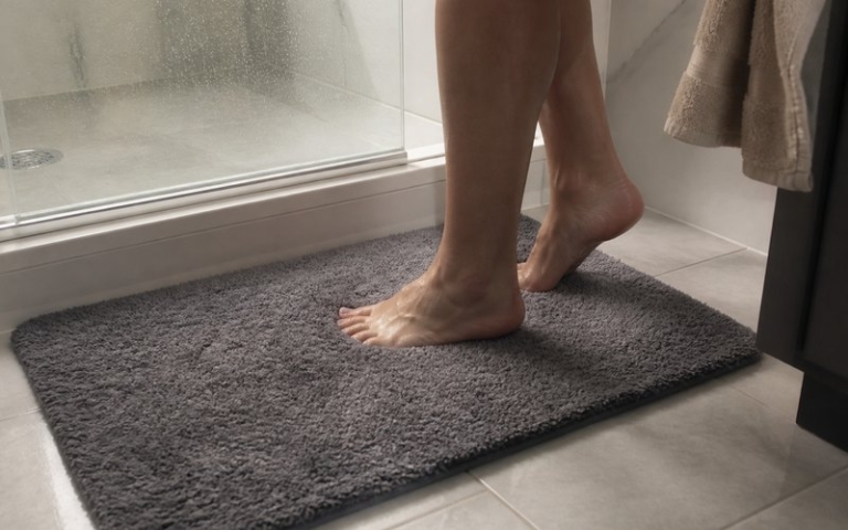 Badematte vor der Dusche auf den Fliesen